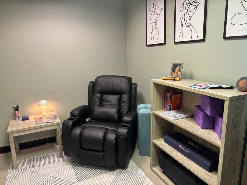 Picture of a room with a recliner and table and bookshelf with yoga mats and blocks