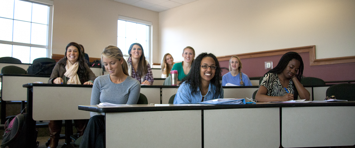 Female students in Daleah Goodwin's Women's Studies class smile in desks